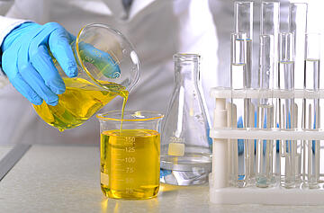 Laboratory beakers and test tubes with plastic gloves in the hands of analysts