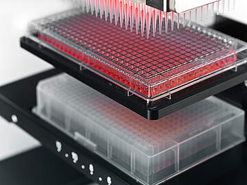 close-up view of a CyBio SELMA 384-channel pipettor after aspirating red liquid from a 384-well plate