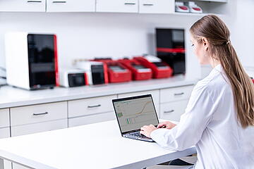 Lab assistant on desk in lab with computer