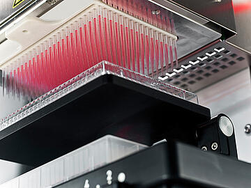 close-up view looking up at a CyBio SELMA 384-channel pipettor after aspirating red liquid from a 384-well plate