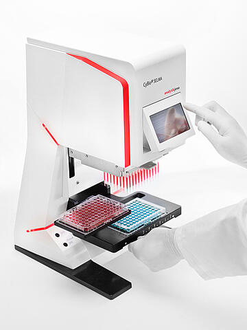 a gloved hand using the touch display panel on a SELMA 96-well pipettor