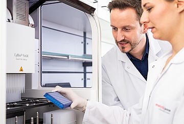 a person loading a 96-well PCR plate onto the deck of a CyBio Felix liquid handler