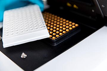 close-up view of a 96-well PCR plate adjacent to the thermal block of a qTOWER iris qPCR instrument