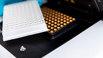 close-up view of a 96-well PCR plate adjacent to the thermal block of a qTOWER iris qPCR instrument